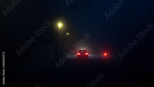 Fotografia Illuminated Bicycle And Car On Street At Night From Rear View