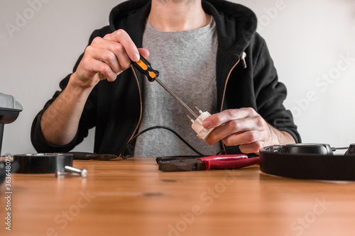 Man at home with screwdriver opening an electrical adapter