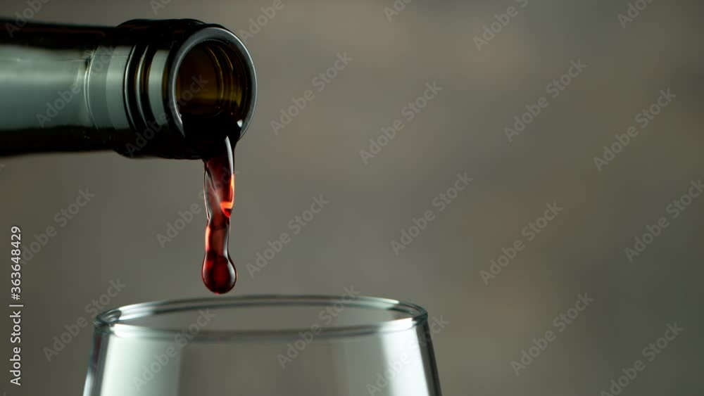 Super Slow Motion Detail Shot of Pouring Red Wine from Bottle on dark Background at 1000fps. Super Slow Motion Detail Shot of Pouring Red Wine from Bottle on dark Background at 1000fps.