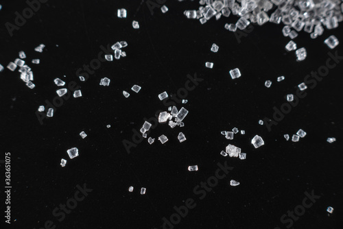 Fullscreen macro closeup with shallow depth of field of small sugar grains on a black background. Texture. Graphic design. photo