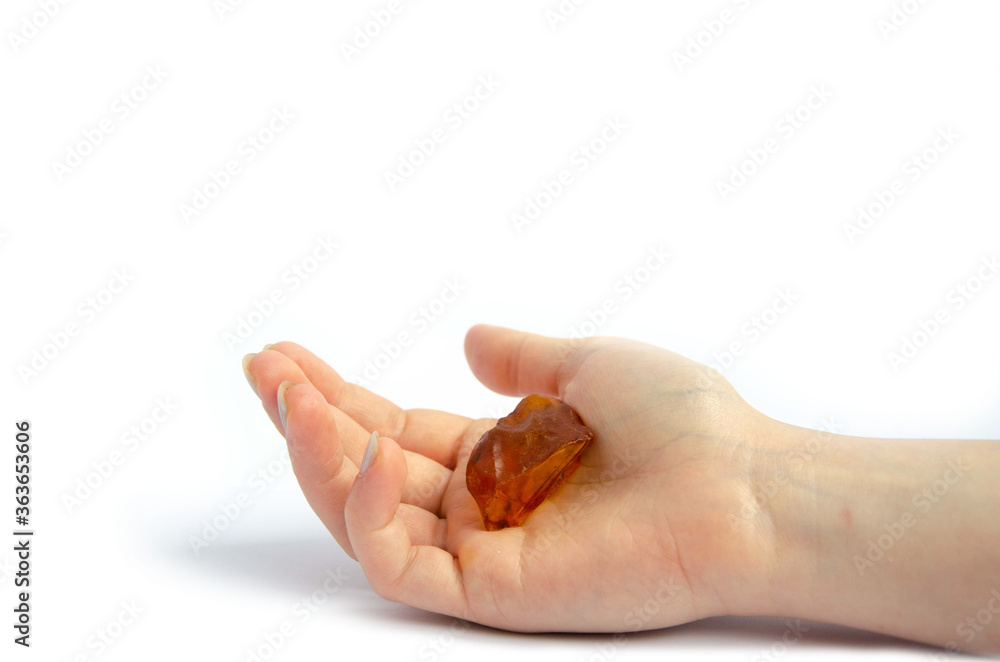 Amber stone. Female hand holds amber on a white background Amber stone. Female hand holds amber on a white background