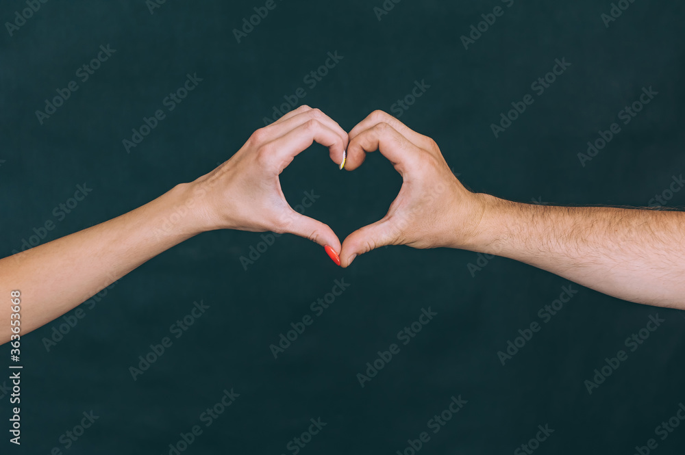 Obraz premium Girl with a guy show hands a sign in the form of a heart. Concept on the theme of lovers.