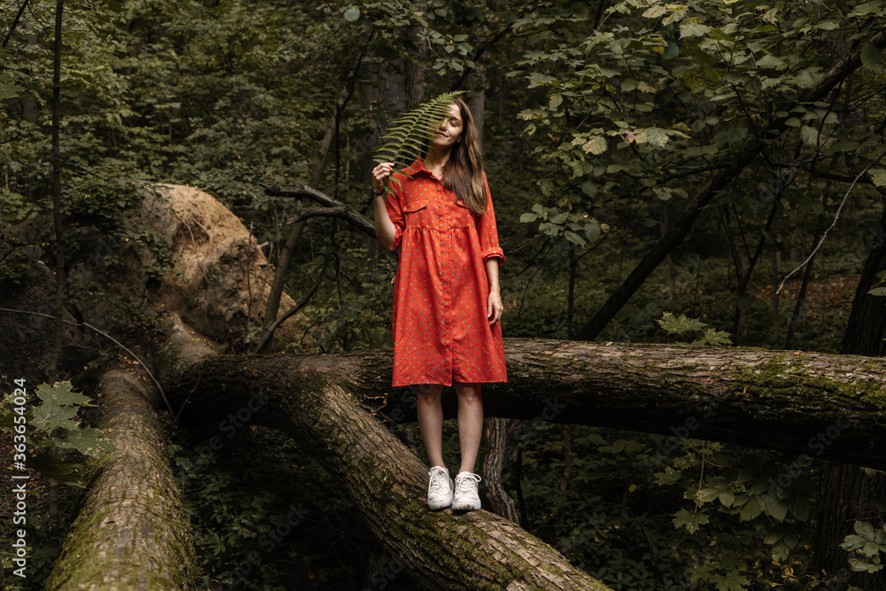 Young woman with fern in forest Young woman with fern in forest