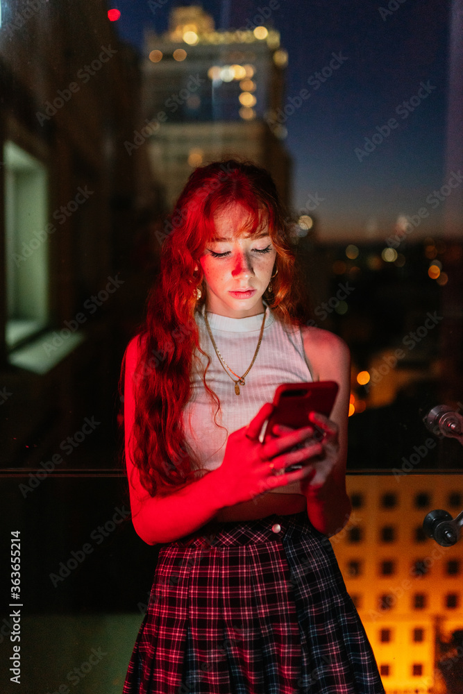 ginger woman using smart phone at night on bokeh background ginger woman using smart phone at night on bokeh background