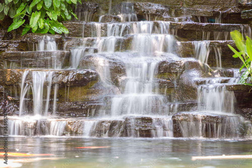 Artificial water fall in the garden. artificial pond with a waterfall in a landscape design. A small artificial waterfall surrounded by rocks Artificial water fall in the garden. artificial pond with a waterfall in a landscape design. A small artificial waterfall surrounded by rocks
