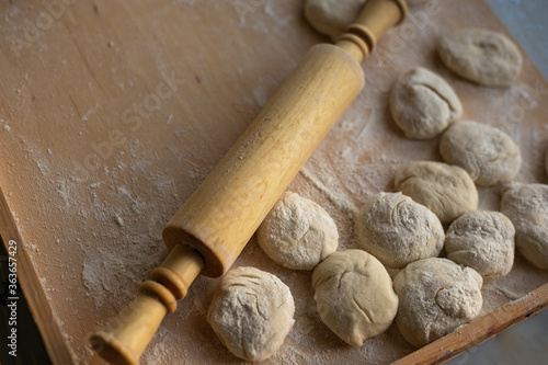 preparing dough for baking, rolling out yeast dough, blanks for pies and a rolling pin are on a wooden board, copy space