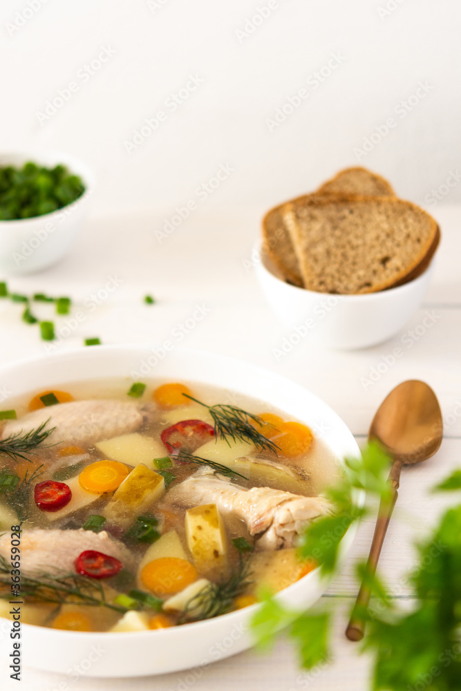 Chicken soup with fresh vegetables, chicken wings broth and young potatoes with onions and carrots, chopped green onions and parsley Chicken soup with fresh vegetables, chicken wings broth and young potatoes with onions and carrots, chopped green onions and parsley