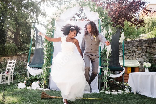 bride and groom jumping over a broom