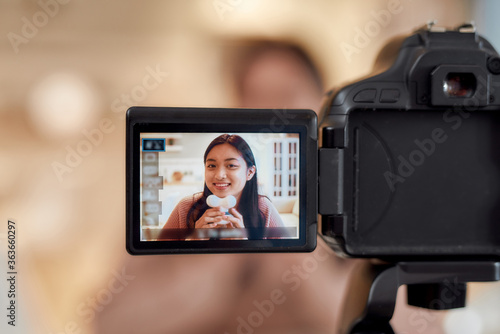 Close up of camera screen. Young female blogger massaging her chin with facial massager while recording a video for her beauty blog. Face lift, anti aging treatment concept