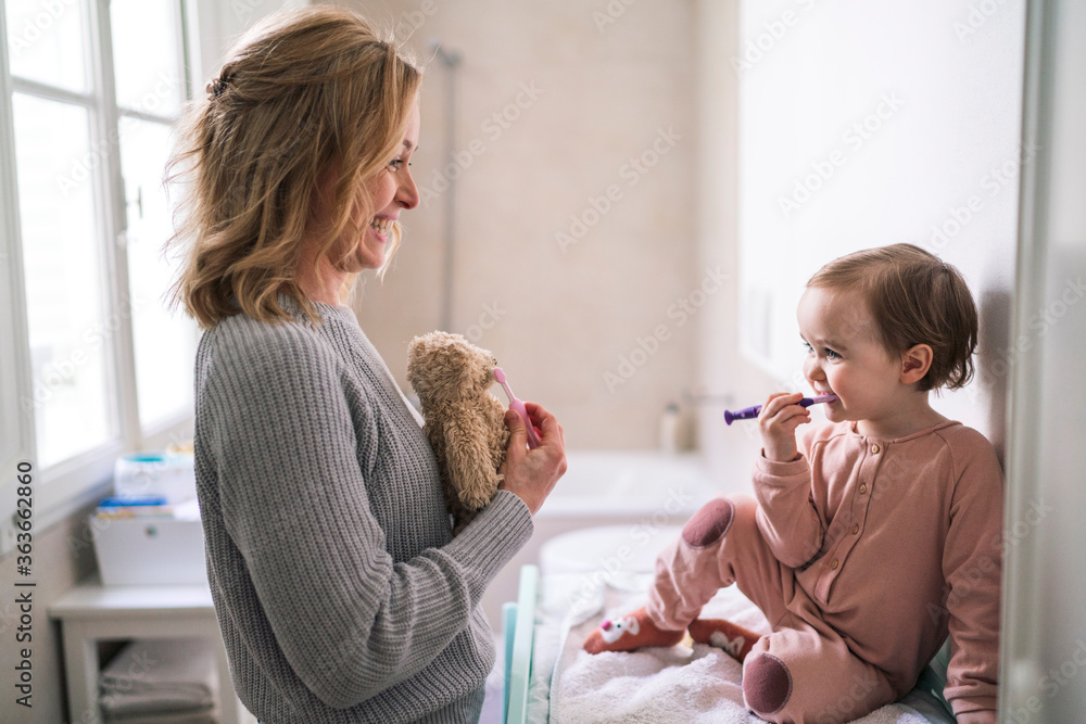 Mother and daughter brushing teeth in bathroom Mother and daughter brushing teeth in bathroom