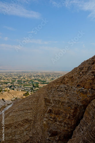 View of city of Jericho from the mountains of temptation. Ancient and hot city at the foot of the mountains, vertical photo.