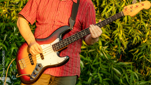 a man playing bass guitar in a Park