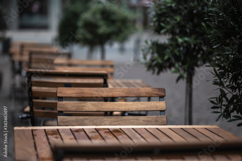 empty chairs and tables with rain drops in front of a restaurant during corona lockdown