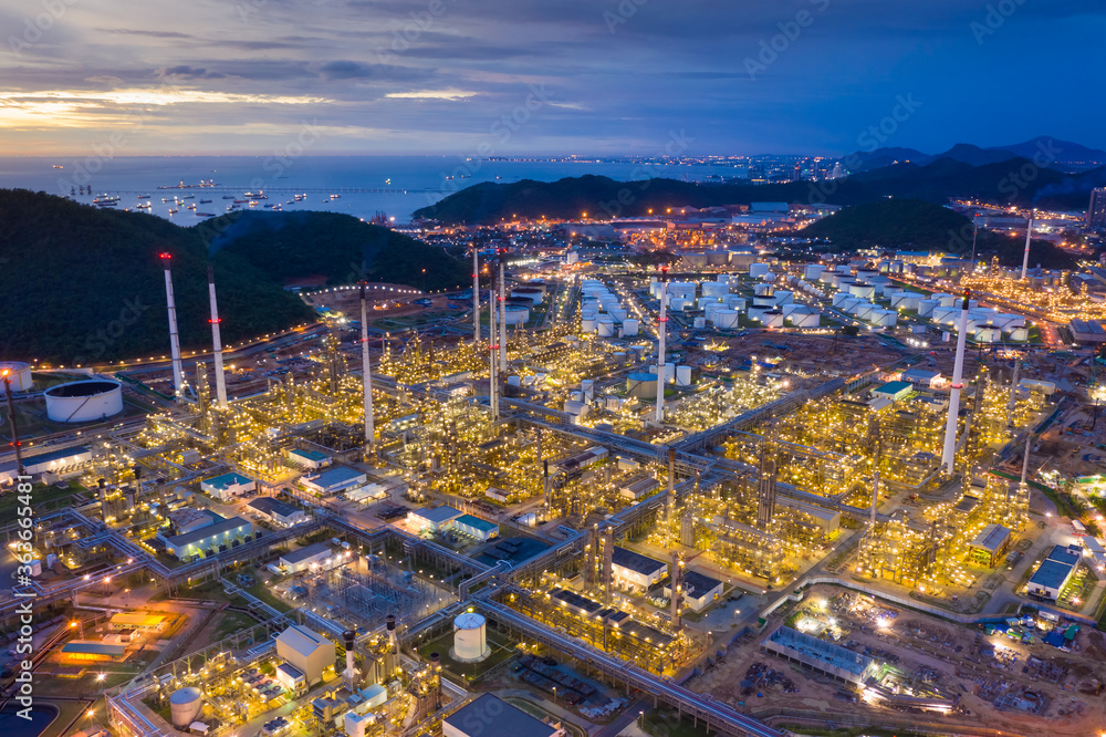 Aerial view of oil refinery plant chemical factory and power plant with many storage tanks and pipelines at sunset.