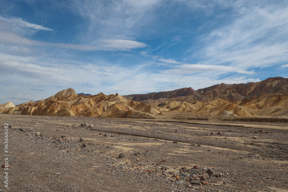 Rocks in Death Valley, blue sky with light clouds.