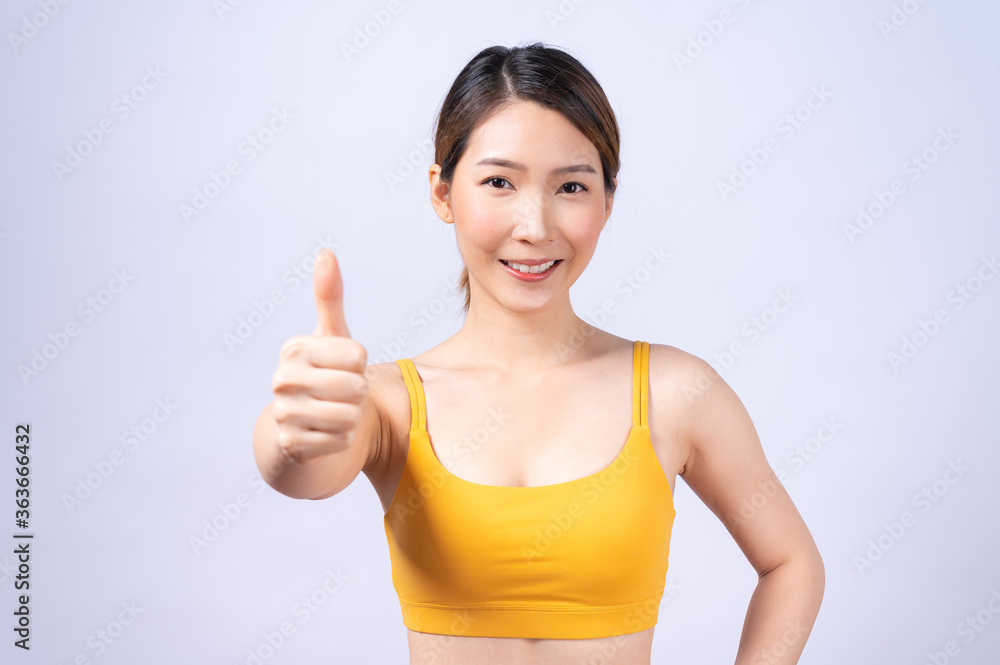Portrait of Asian sporty woman giving thumb up isolated on white background. concept of healthy lifestyle. Portrait of Asian sporty woman giving thumb up isolated on white background. concept of healthy lifestyle.