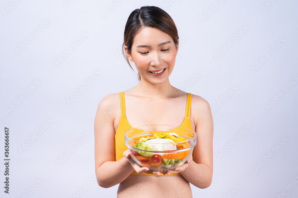 Healthy lifestyle, Vegetarian, diet concept. Asian woman in sportswear holding salad bowl isolated on white background.