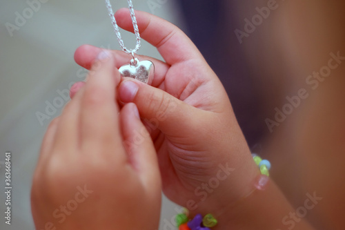 Children's hands holding a beautiful chain with a pendant so close