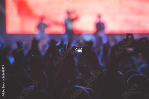 A crowded concert hall with scene stage lights, rock show performance, with people silhouettes during live music show performance with crowd of audience © tsuguliev