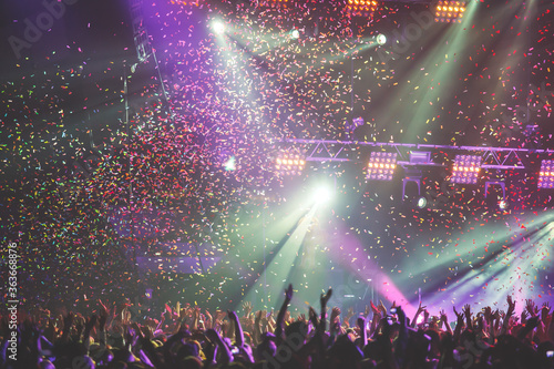 A crowded concert hall with scene stage lights, rock show performance, with people silhouettes during live music show performance with crowd of audience photo