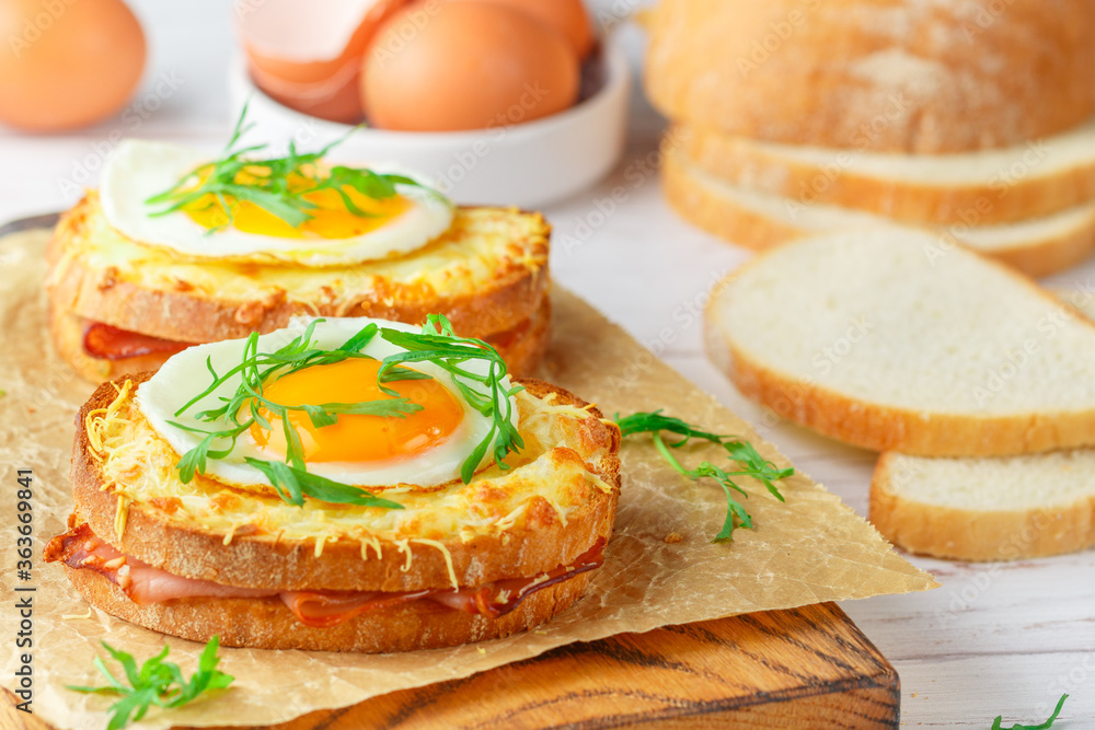 Sandwich white bread with ham or bacon, mustard, cheese, Bechamel sauce, watercress and eggs. CROQUE MADAME. traditional French cuisine. Selective focus