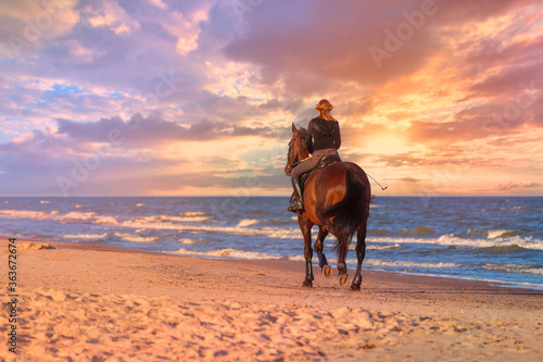 The girl on the horse is enjoying the horse ride on the shores of the Baltic sea. Ventspils, Latvia.