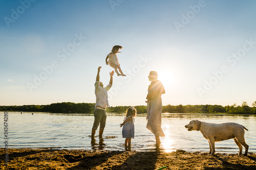 Father throwing young girl into the air at sunset