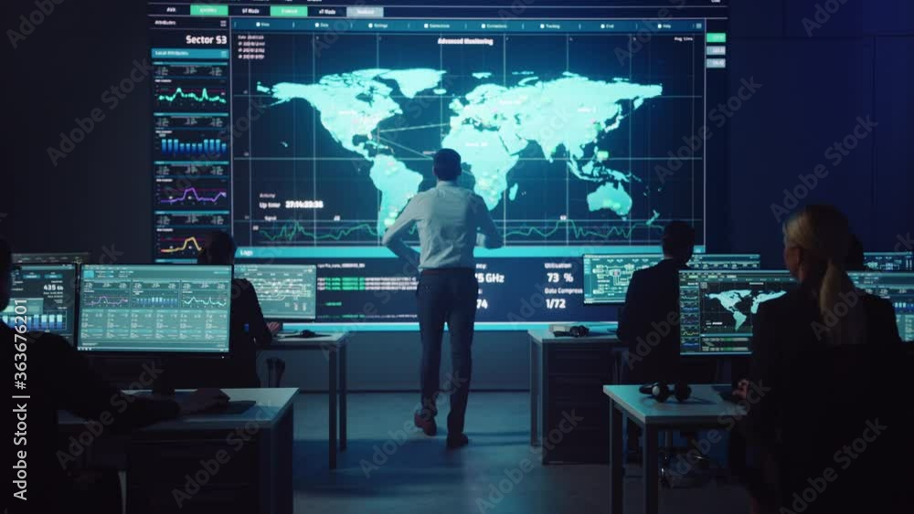 Project manager Walks to a Big Screen with Neural Network. Team of Professional Computer Data Science Engineers Work on Desktops in a Dark System Control and Monitoring Telecommunications Office.