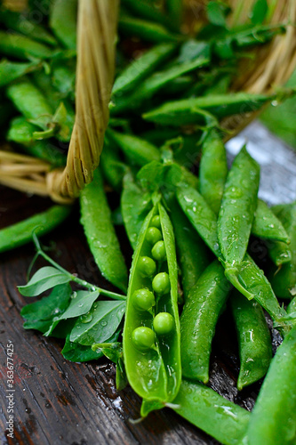 Fotografie Green pea pods in drops of water close-up on a wooden table