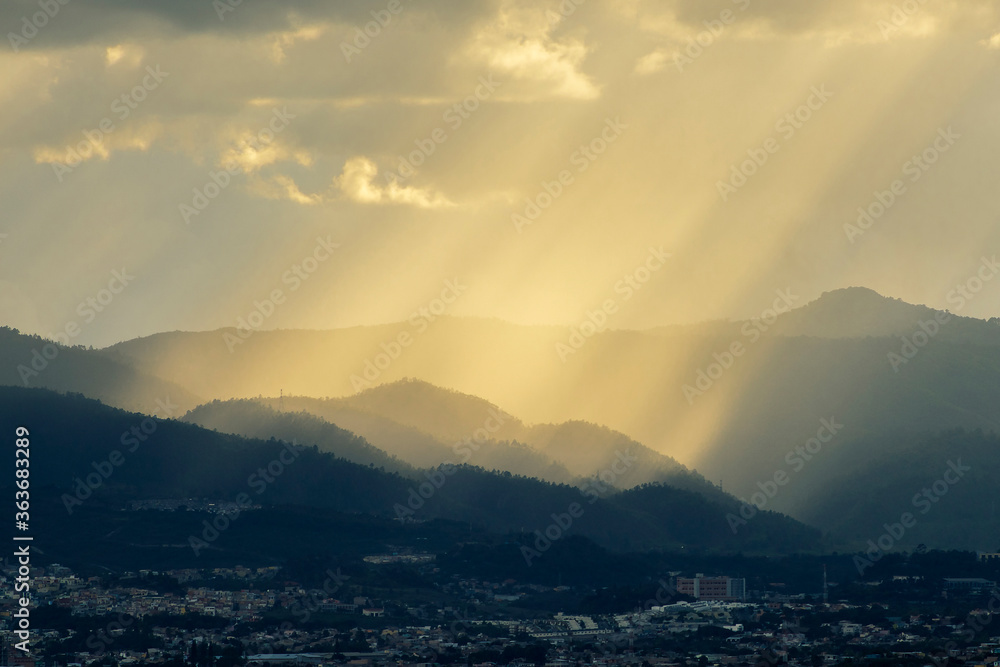Diagonal sunrays falling down over a hill