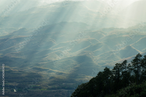 Sunrays in diagonal falling over hills at sunset