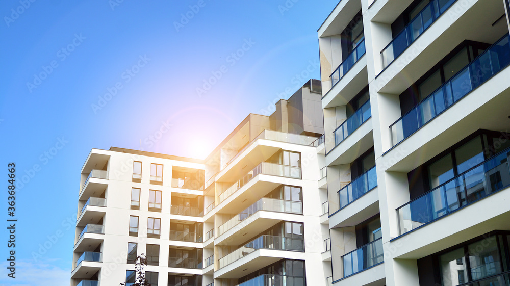 Modern apartment buildings on a sunny day with a blue sky. Facade of a modern apartment building. Glass surface with sunlight.