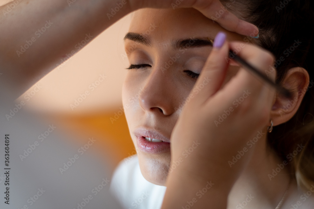 blonde model with white skin being made up with a brush. Eyes closed and relaxed blonde model with white skin being made up with a brush. Eyes closed and relaxed