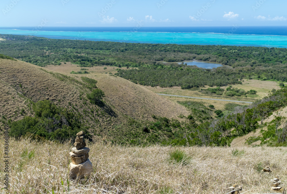 Panoramic view of Deva domain, New Caledonia. Pebbles piling up on the foreground.  Turquoise water and blue sky