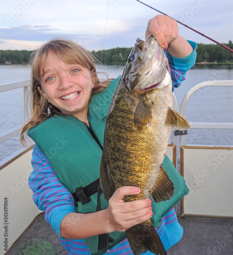 Smiling young girl holding large smallmouth bass fish