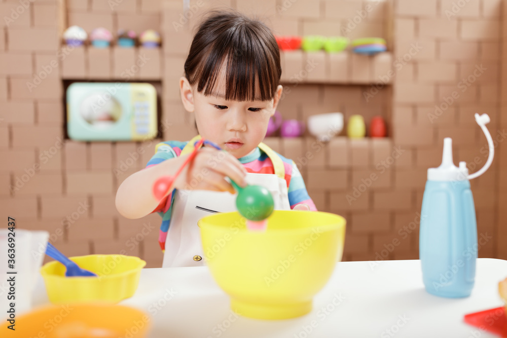 toddler girl pretend play food preparing role against cardboard blocks kitchen background toddler girl pretend play food preparing role against cardboard blocks kitchen background