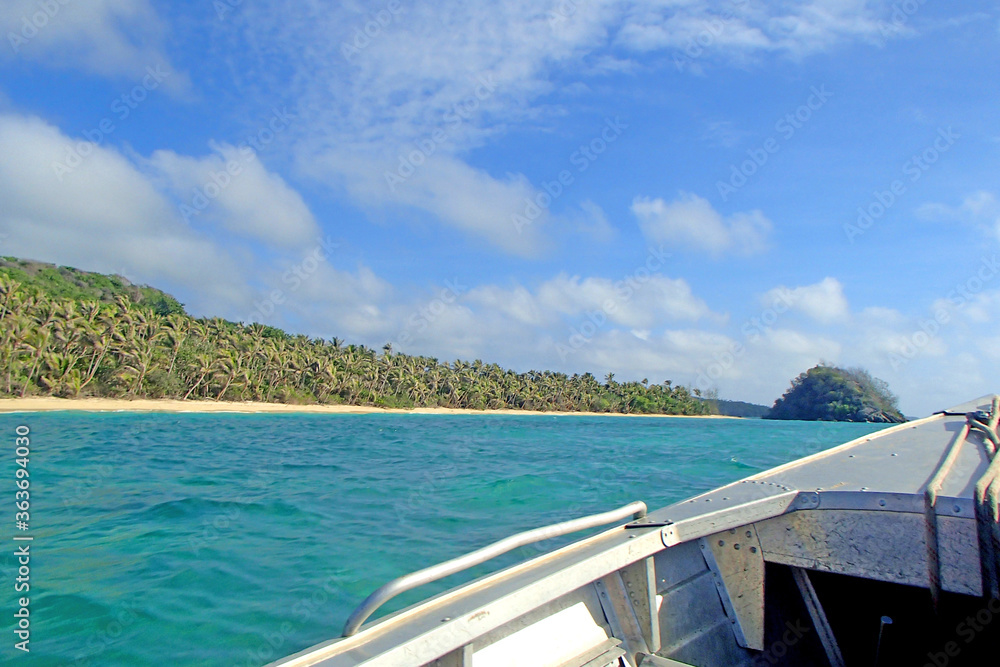 Boat view on one of the tropical islands of Fiji, beach, rock and full of palm tree