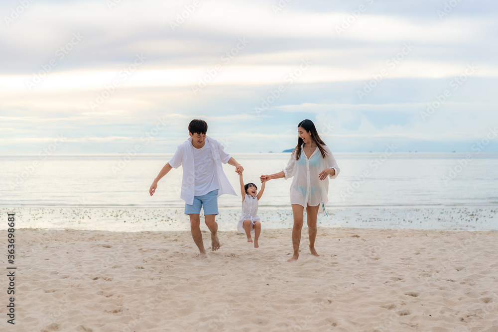 Happy Asian family holidays during joyful father, mother and daughter running together along summer sunset sea. Happy family travel on beach in holiday, Summer and vacation.