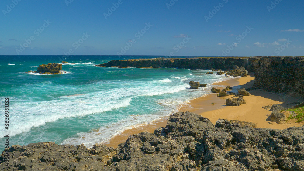 Foaming ocean waves wash the small sandy bay surrounded by rugged rocky cliffs Foaming ocean waves wash the small sandy bay surrounded by rugged rocky cliffs