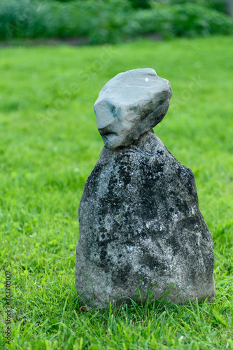 a stone figure stands on the grass