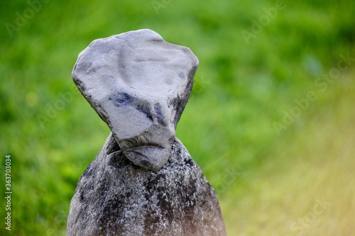 a stone figure stands on the grass