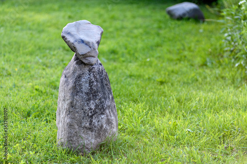 a stone figure stands on the grass
