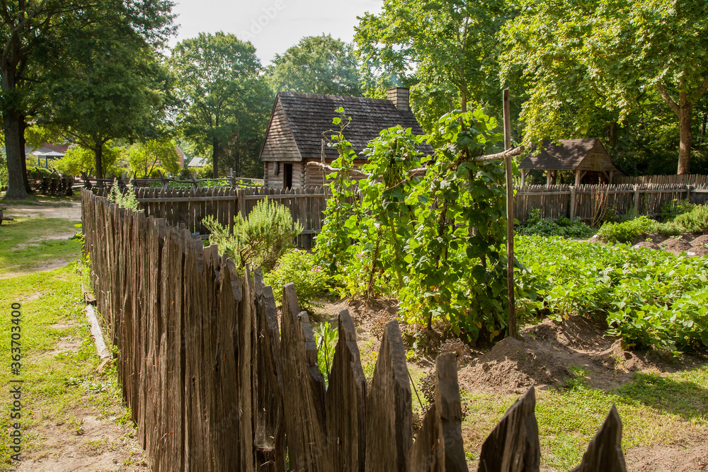 Naklejka premium A garden with a rustic building in Historic Yorktown village, part of Colonial National Historic Park, Virginia, established by the Act for Ports of 1691