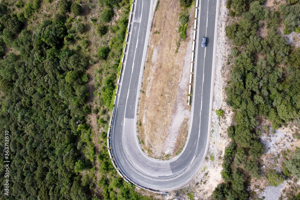 Aerial view of winding road in high mountain pass trough green pine woods. High quality photo