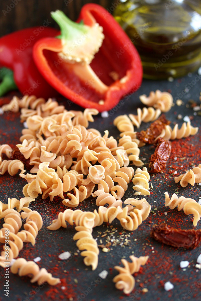 raw fusilli paprika pasta, close-up on a black background. homemade pasta without dyes from durum wheat. raw fusilli paprika pasta, close-up on a black background. homemade pasta without dyes from durum wheat.