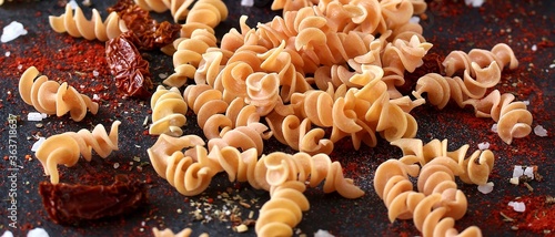 raw fusilli paprika pasta, close-up on a black background. homemade pasta without dyes from durum wheat. 