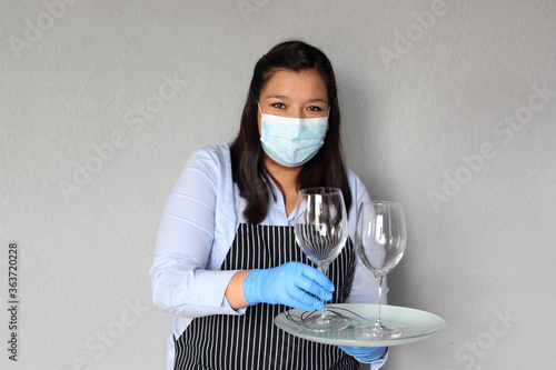 Latin woman waitress with tray and glasses working with face masks and protective gloves, new normal by covid-19 photo