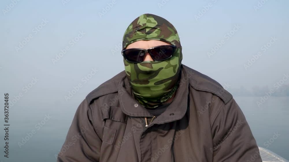 Man with a camuflage mask on a boat Man with a camuflage mask on a boat