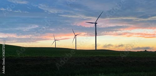 wind turbines silhouettes on farm field sunset