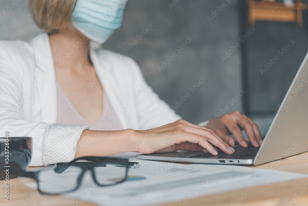 Naklejka premium Business womanl wears a mask to protect against viruses, sit on a laptop, newnormal during the coronavirus epidemic
